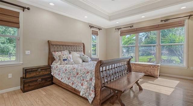 bedroom featuring light hardwood / wood-style flooring, a tray ceiling, and ornamental molding