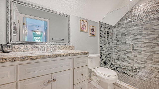 bathroom with ceiling fan, vanity with extensive cabinet space, tile floors, toilet, and a shower with shower door