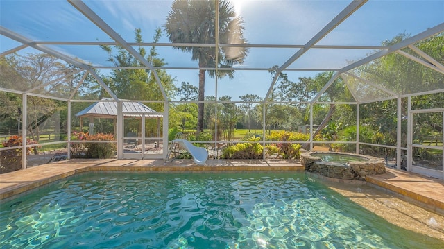 view of swimming pool featuring a lanai, a water slide, and an in ground hot tub