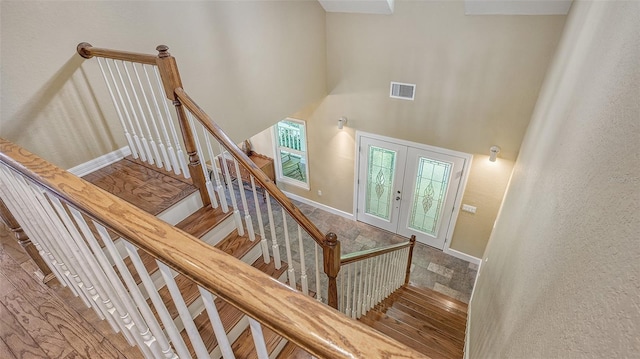 stairway with french doors, dark hardwood / wood-style floors, and a high ceiling