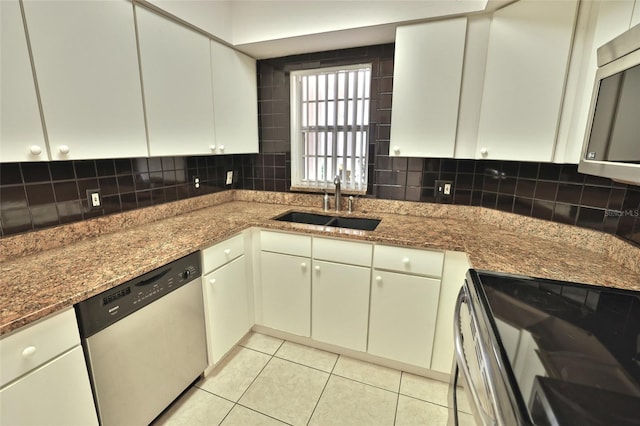 kitchen with dark stone countertops, sink, light tile patterned flooring, and stainless steel appliances