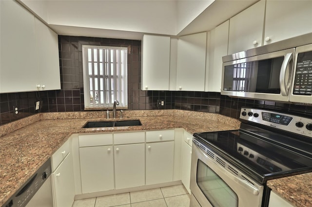 kitchen featuring white cabinets, sink, light tile patterned floors, stone countertops, and stainless steel appliances