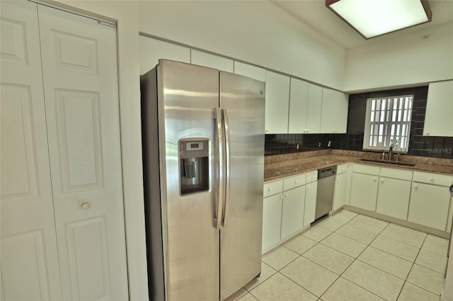 kitchen with decorative backsplash, appliances with stainless steel finishes, sink, white cabinetry, and light tile patterned flooring