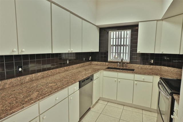 kitchen with appliances with stainless steel finishes, backsplash, dark stone counters, sink, and light tile patterned flooring