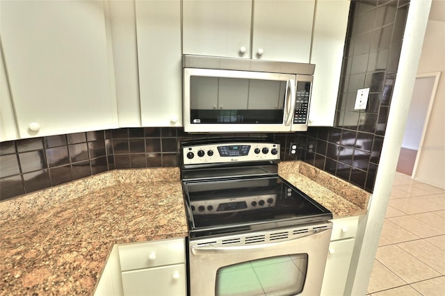 kitchen featuring light tile patterned floors, backsplash, stainless steel appliances, and dark stone countertops