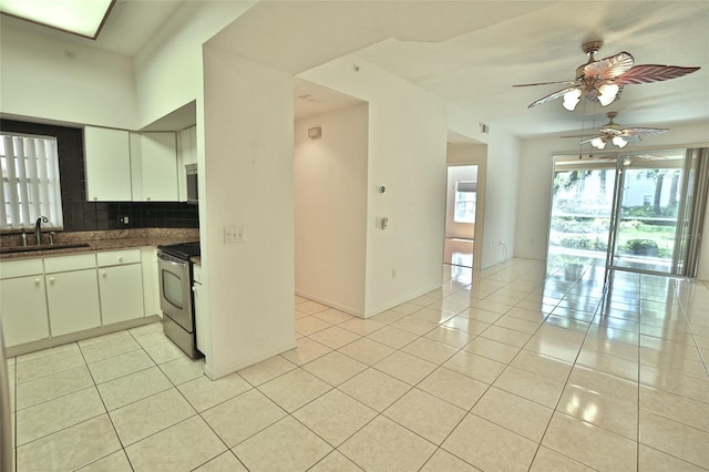 kitchen featuring white cabinets, sink, stainless steel electric range oven, light tile patterned floors, and tasteful backsplash