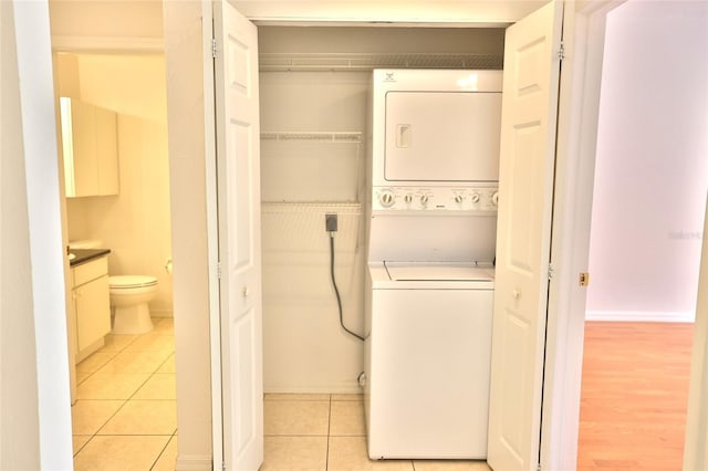 clothes washing area with light tile patterned flooring and stacked washer and dryer