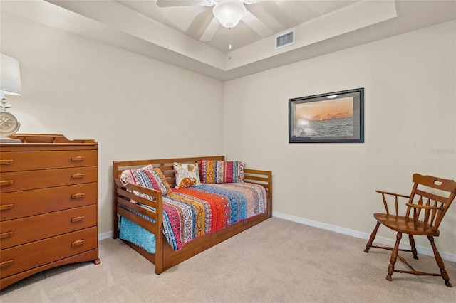 bedroom featuring ceiling fan, light colored carpet, and a tray ceiling