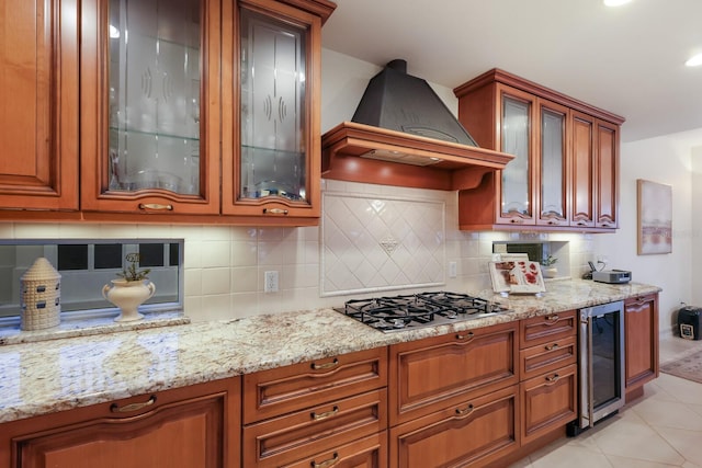 kitchen with backsplash, premium range hood, light tile flooring, wine cooler, and stainless steel gas cooktop