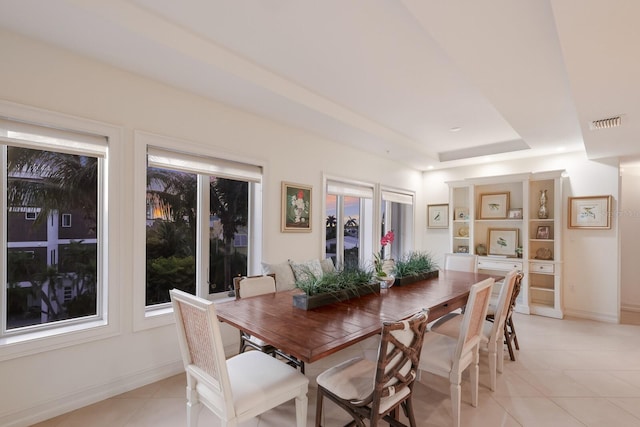 dining area with light tile flooring and a tray ceiling