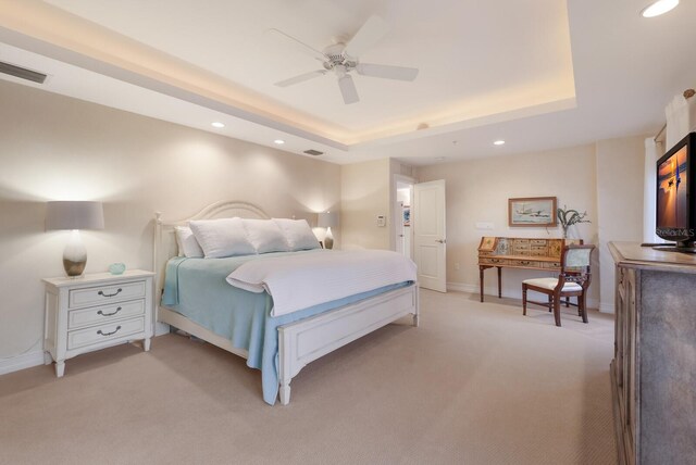 carpeted bedroom with ceiling fan and a raised ceiling