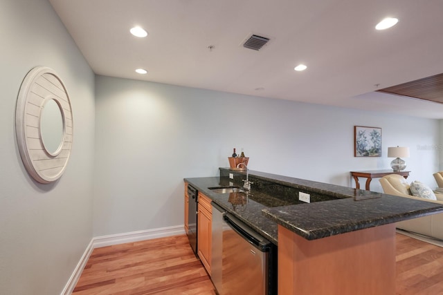 kitchen with kitchen peninsula, light hardwood / wood-style floors, dark stone countertops, sink, and stainless steel dishwasher