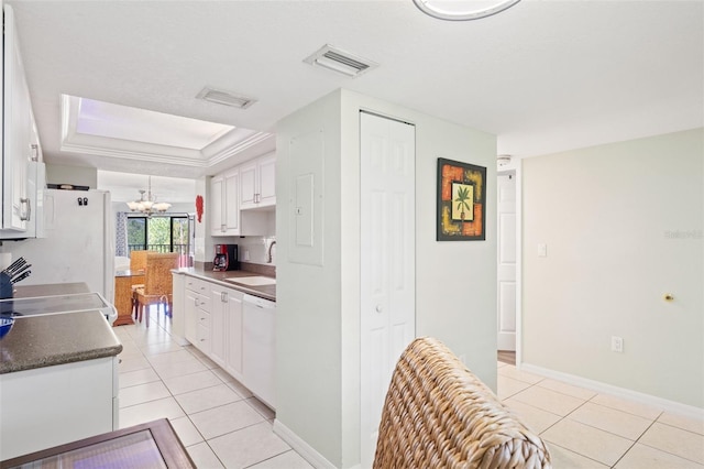 kitchen with sink, white cabinetry, light tile floors, and a tray ceiling