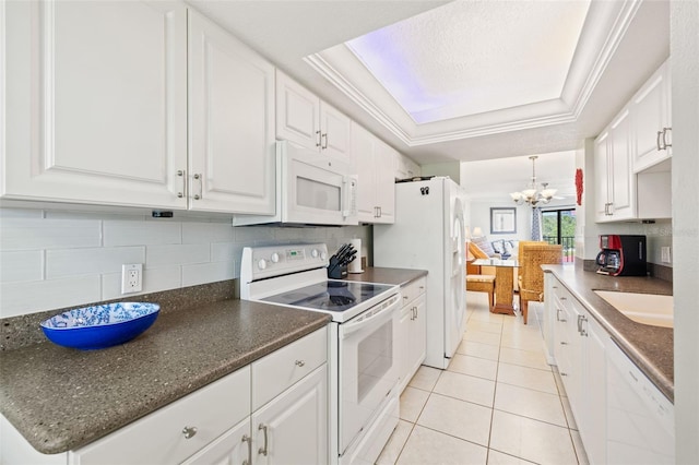 kitchen featuring white appliances, a tray ceiling, backsplash, ornamental molding, and a notable chandelier