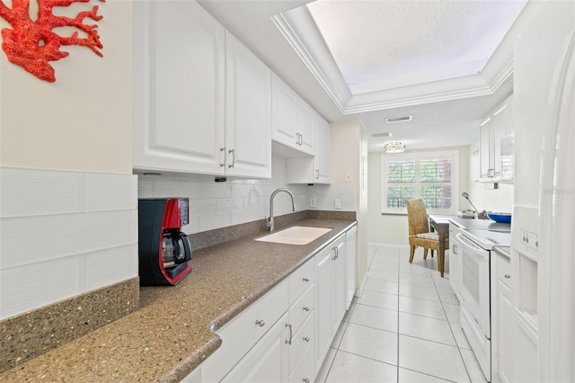 kitchen with white appliances, a tray ceiling, white cabinets, sink, and ornamental molding