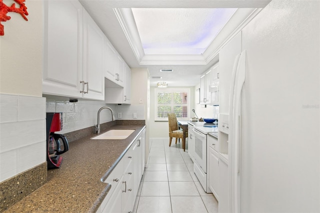 kitchen featuring sink, white appliances, tasteful backsplash, white cabinetry, and a tray ceiling