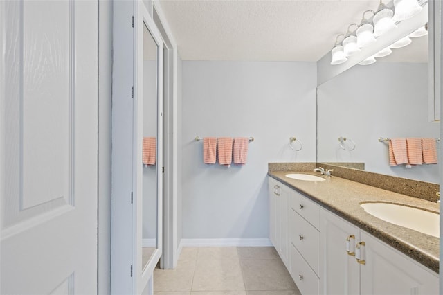 bathroom featuring dual sinks, vanity with extensive cabinet space, tile floors, and a textured ceiling