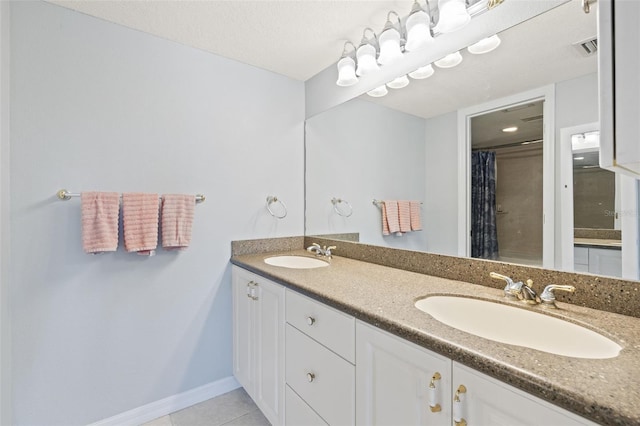 bathroom featuring dual sinks, oversized vanity, a textured ceiling, and tile flooring