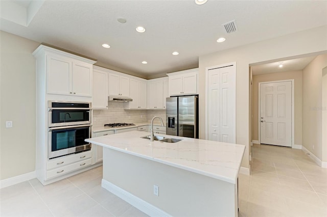 kitchen with appliances with stainless steel finishes, white cabinetry, sink, and an island with sink