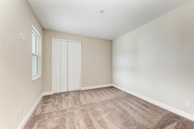 unfurnished bedroom featuring light carpet and a closet