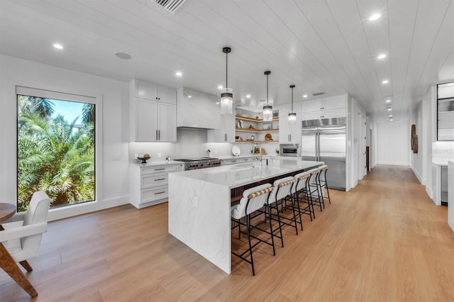 kitchen featuring white cabinetry, built in fridge, light hardwood / wood-style flooring, and a healthy amount of sunlight