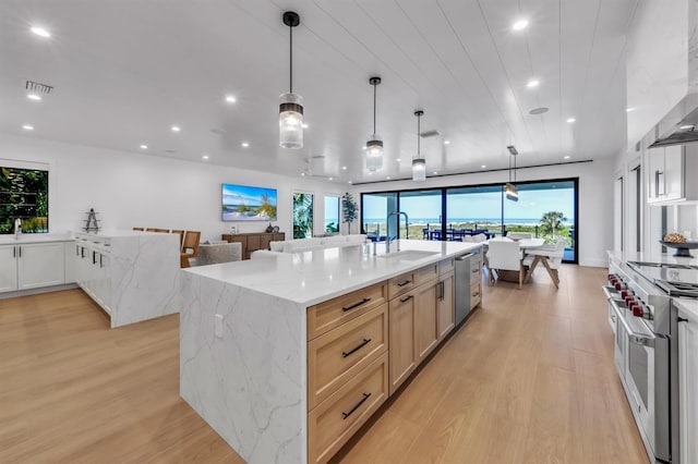 kitchen with pendant lighting, sink, a large island, stainless steel appliances, and light brown cabinets