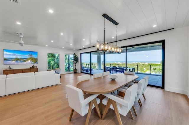 dining room featuring ceiling fan with notable chandelier and light hardwood / wood-style flooring