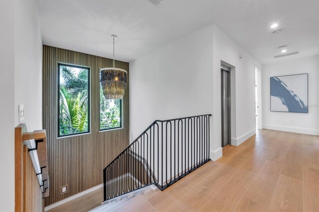 hall with an inviting chandelier and wood-type flooring