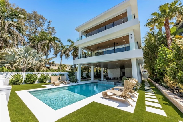 rear view of house with a fenced in pool, a balcony, a yard, and ceiling fan