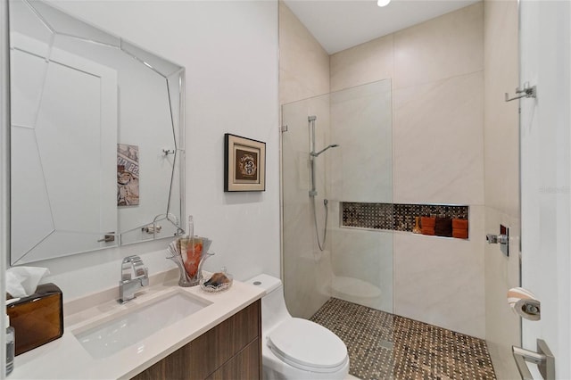 bathroom featuring tiled shower, vanity, and toilet