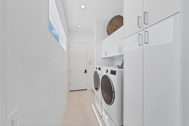 laundry area featuring cabinets, separate washer and dryer, and light tile floors