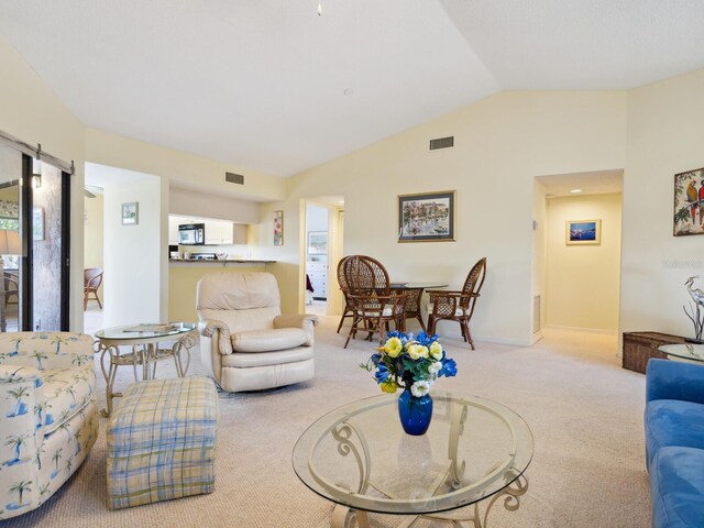 carpeted living room with vaulted ceiling, a healthy amount of sunlight, and a barn door