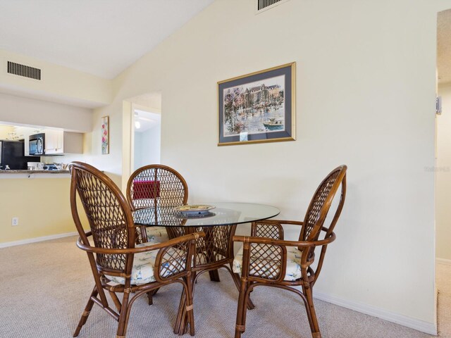 dining area featuring vaulted ceiling and carpet flooring