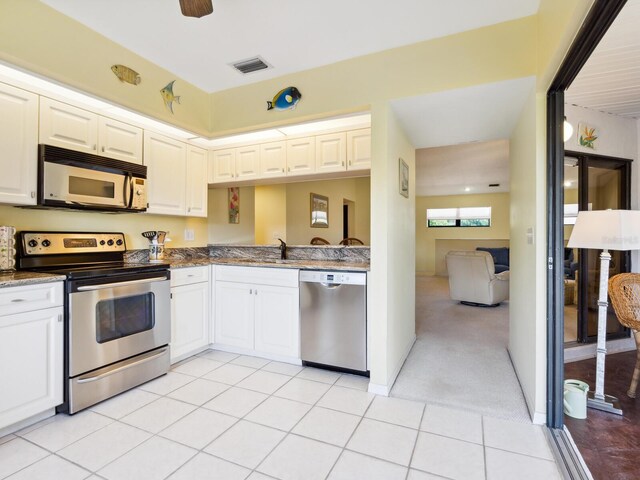 kitchen featuring appliances with stainless steel finishes, light carpet, dark stone counters, white cabinets, and sink