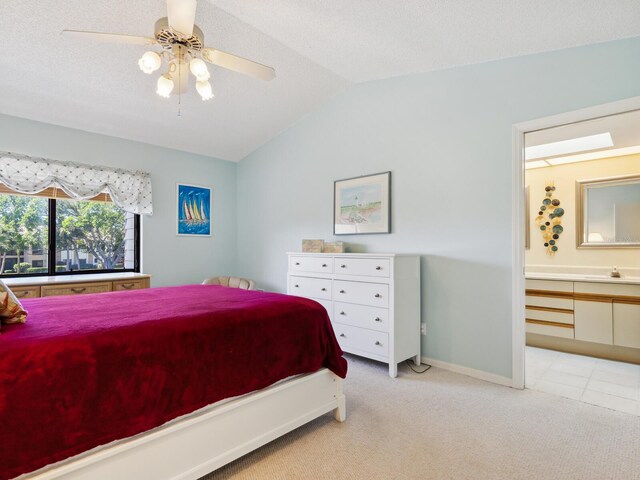 bedroom featuring ensuite bathroom, ceiling fan, vaulted ceiling, a textured ceiling, and light carpet