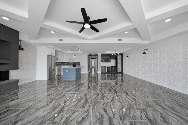 unfurnished living room featuring ceiling fan with notable chandelier, light tile floors, tile walls, and coffered ceiling