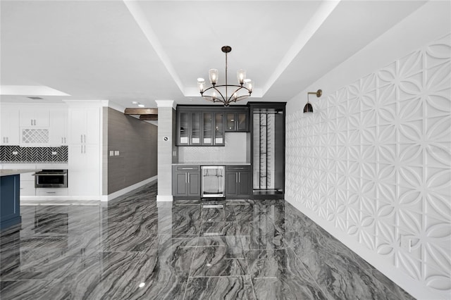 interior space with dark tile flooring, a raised ceiling, and an inviting chandelier