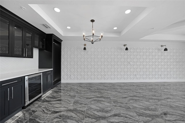 kitchen featuring beverage cooler, dark tile floors, a notable chandelier, a raised ceiling, and decorative light fixtures