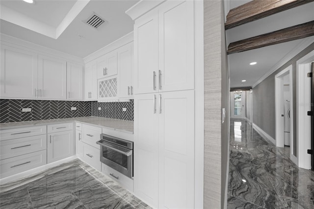 kitchen with backsplash, light stone counters, dark tile flooring, white cabinetry, and stainless steel oven