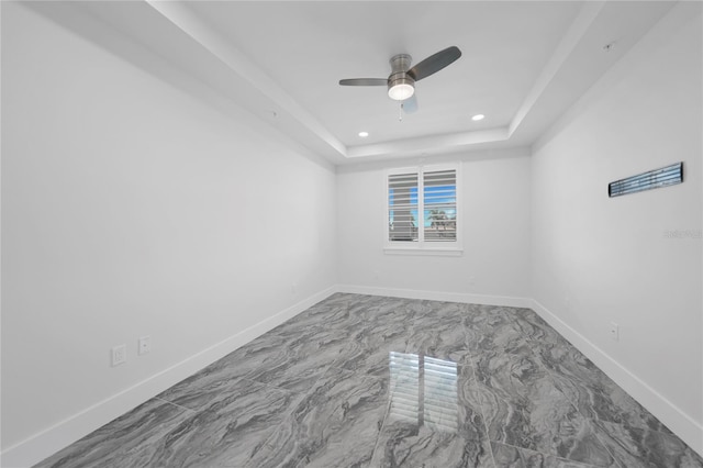 unfurnished room with ceiling fan, a tray ceiling, and tile flooring