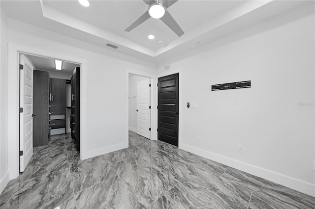 unfurnished bedroom with a raised ceiling, ceiling fan, and tile floors