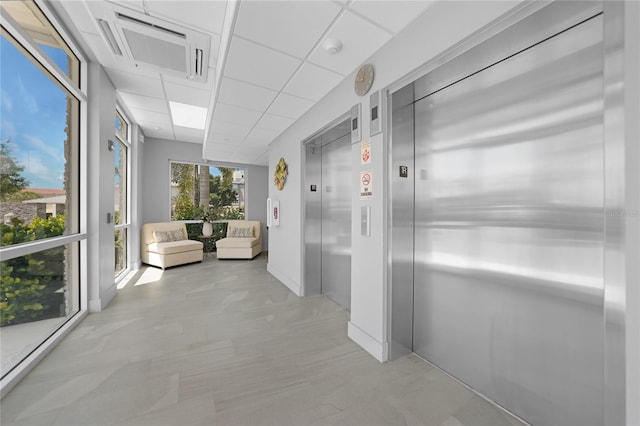 corridor featuring elevator and a paneled ceiling