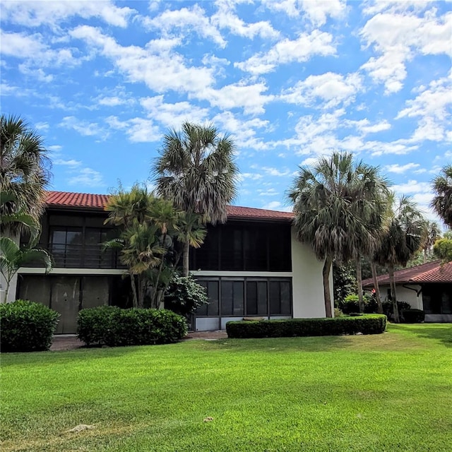 rear view of house featuring a lawn and a sunroom