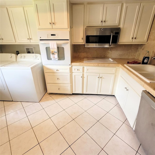 kitchen with white cabinets, light tile flooring, sink, white oven, and dishwasher