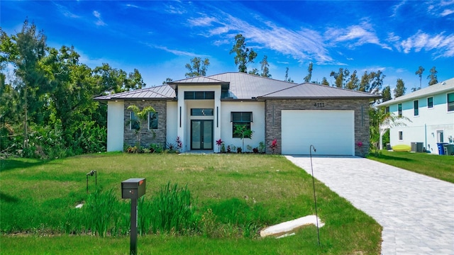 view of front of home featuring decorative driveway, an attached garage, a standing seam roof, stone siding, and a front lawn