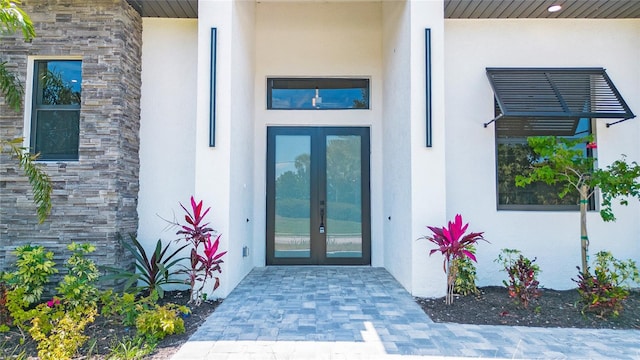 4111 Williams Rd, Estero, FL 33928 - view of exterior entry with stone siding, french doors, and stucco siding