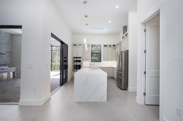 4111 Williams Rd, Estero, FL 33928 - kitchen featuring tasteful backsplash, glass insert cabinets, appliances with stainless steel finishes, a kitchen island with sink, and a sink