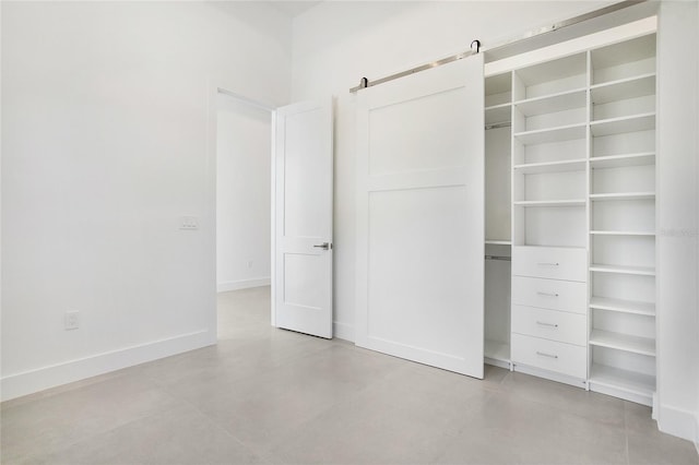 4111 Williams Rd, Estero, FL 33928 - unfurnished bedroom featuring baseboards, a barn door, a closet, and finished concrete floors