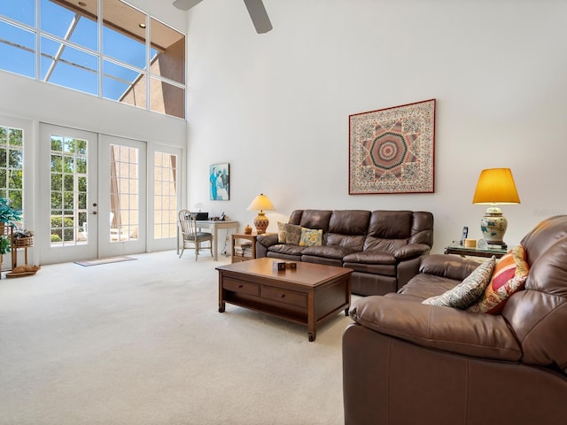 carpeted living room with french doors, a towering ceiling, and ceiling fan