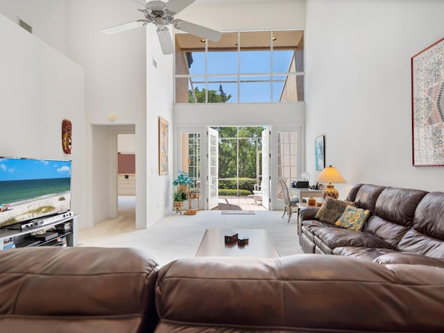 living room featuring a water view, ceiling fan, a towering ceiling, and light carpet